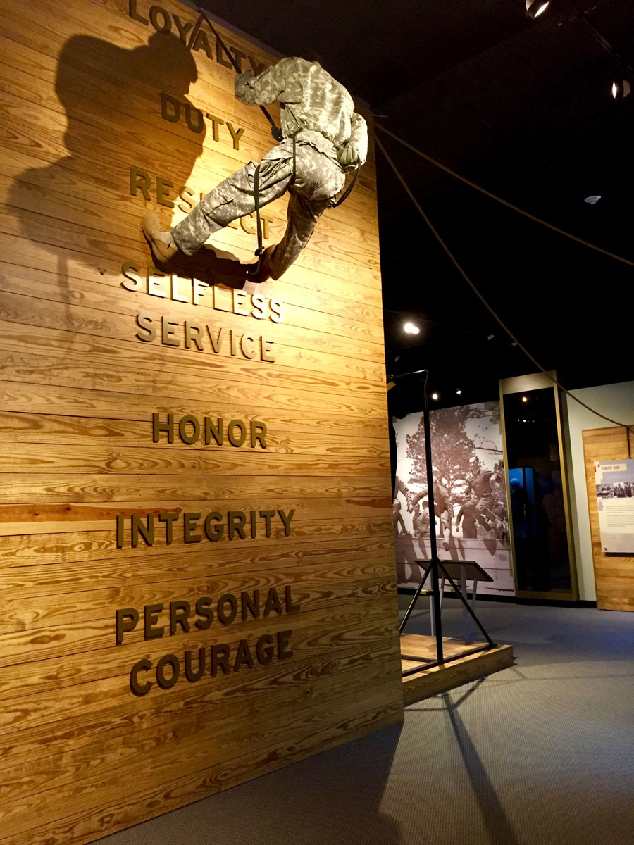 A mannequin Soldier scaling a wooden wall inside the US Army Basic Combat Training Musuem.